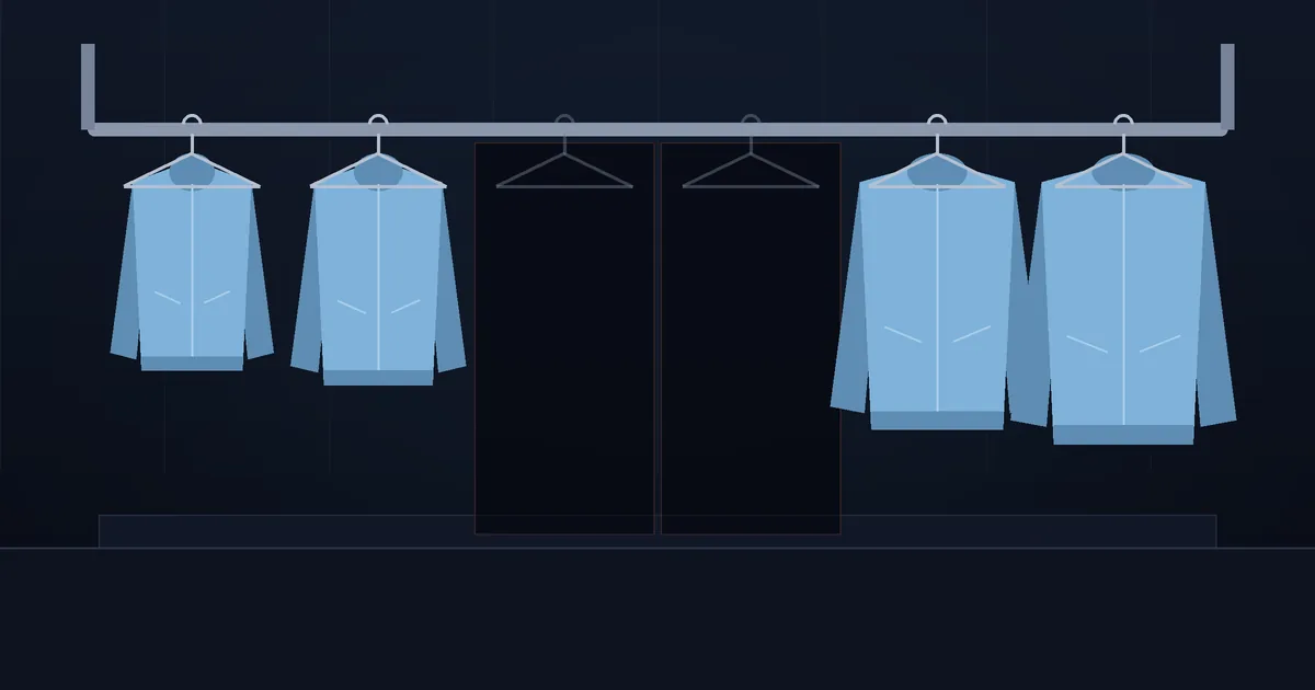 A dark shop display with a row of identical jackets in different sizes on hangers, two hangers in the middle empty and shaded